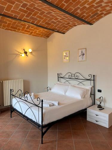 a bedroom with a bed with a wrought iron bed frame at Tenuta Agricola La Cava- Cantina e Agriturismo in San Damiano dʼAsti