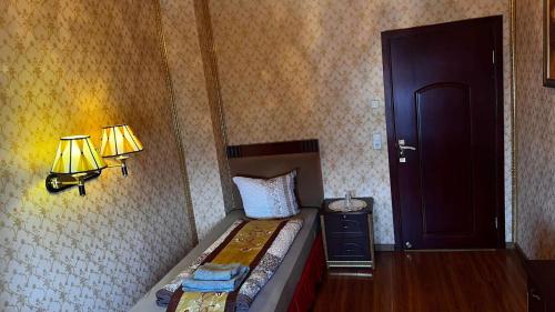 a bedroom with a bed and two lamps and a door at Hotel & Restaurant Com Viet in Oschatz