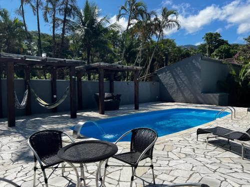 uma piscina com cadeiras e uma rede de descanso junto a uma cerca em Sunset Maresias- Casas e Chalés C3 em Maresias