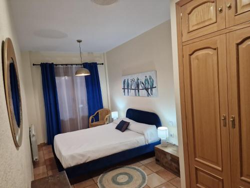 a small bedroom with a bed and blue curtains at La casa del patio ATBA00260 in Zafra
