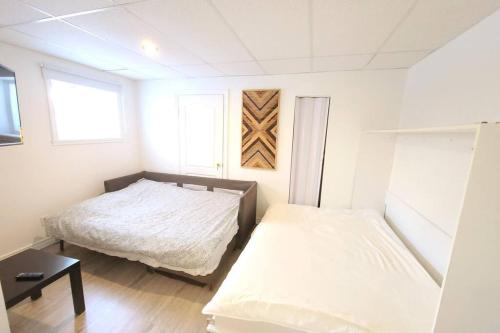 um pequeno quarto com 2 camas e uma janela em Cozy 1BR in Vieux-Longueuil +parking 14min Downtown em Longueuil