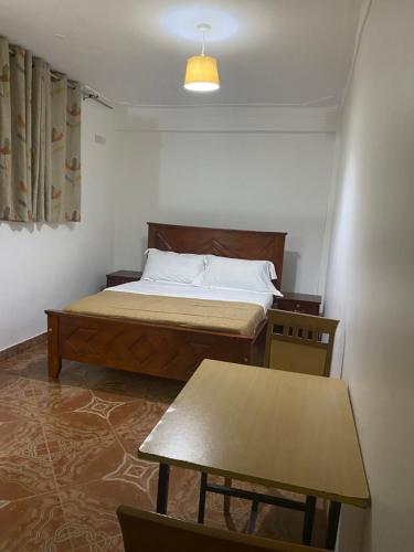 a small bedroom with a bed and a table at Ingrid's Place - Namugongo in Namugongo