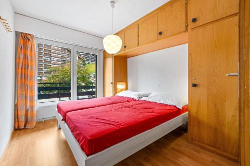 ein Schlafzimmer mit einem roten Bett und einem Fenster in der Unterkunft Christiania I E4 - 6 pers -pres des pistes in Nendaz