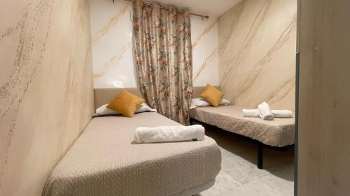 ベナルマデナにあるApartamento con vista a la piscinaの小さな部屋のベッド2台 カーテン付