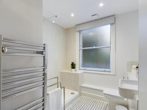 baño con lavabo y aseo y ventana en The Grove King bed Wi-Fi EV Charger en Cheltenham