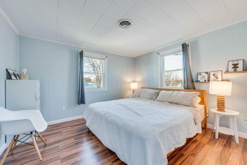 a bedroom with a bed and a chair and two windows at Badgers Island Condo Near Restaurants and Marina! in Kittery