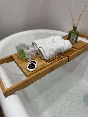 El baño incluye una bandeja de madera en el aseo con toallas y tazas. en Barn with Hot Tub, en Goffs Oak