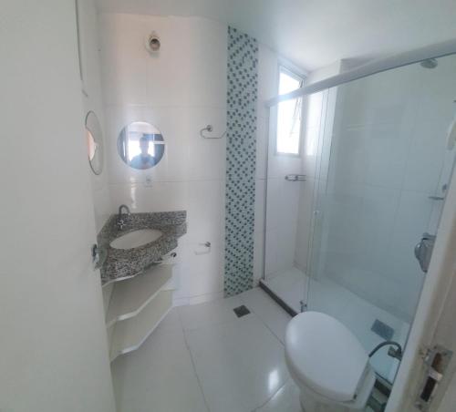 a white bathroom with a toilet and a sink at Cobertura Braga in Cabo Frio