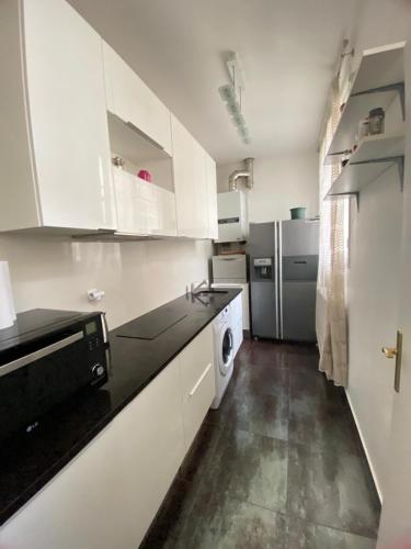  La cuisine est équipée de placards blancs et d'un réfrigérateur. dans l'établissement Haussmannien moderne 2 pièces quartier Europe du 8éme, à Paris