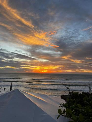 a sunset on a beach with the ocean at Graffi Beach House in Florianópolis