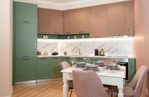 a kitchen with green cabinets and a white table and chairs at Loris Apartaments 205 in Durrës