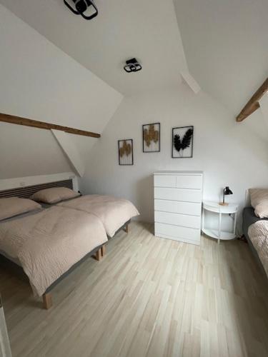 a white bedroom with two beds and a dresser at FREIGEIST ZeitRaum in Haßloch