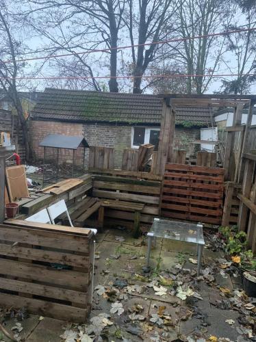 a backyard with wooden pallets and a fence at Spacious 1 bedroom en-suite, kitchen and garden space in Ilford