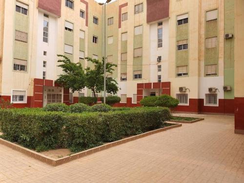 a courtyard of a building with bushes and buildings at Mooi appartement, Route el Aounia Oujda in Oujda