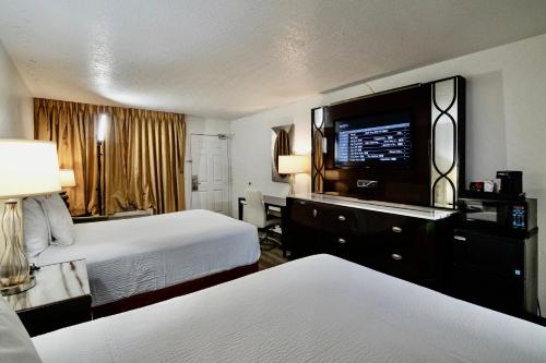 a hotel room with two beds and a flat screen tv at Ramada by Wyndham Yuma in Yuma