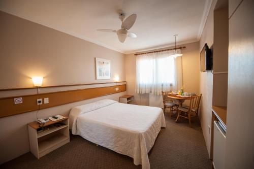 ベント・ゴンサルベスにあるFarina Park Hotelのベッドとテーブルが備わるホテルルームです。