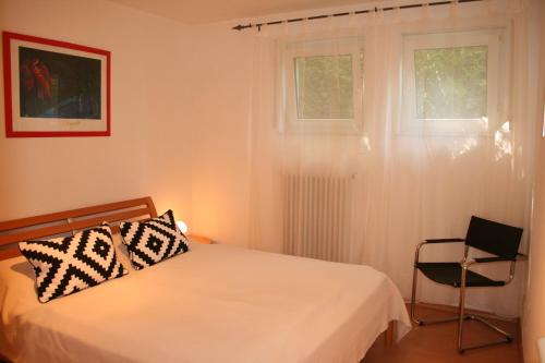 ein Schlafzimmer mit einem Bett, einem Stuhl und einem Fenster in der Unterkunft Ferienwohnung am Schlosspark in Weinheim