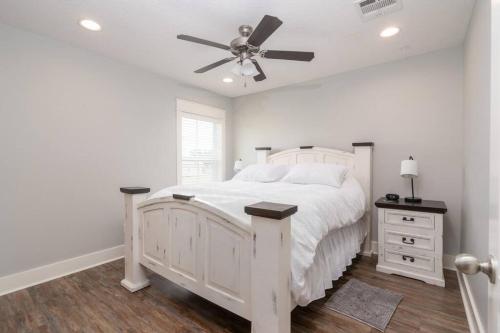 a white bedroom with a white bed and a ceiling fan at Bright Townhouse Downtown Lake Charles in Lake Charles