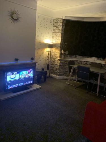 ein Wohnzimmer mit einem Flachbild-TV und einem Tisch in der Unterkunft Spacious 1 bedroom en-suite, kitchen and garden space in Ilford