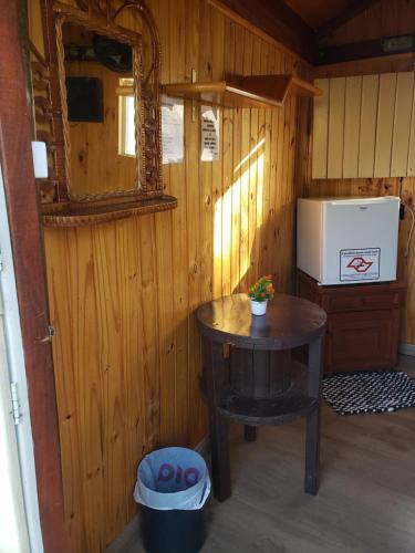 um pequeno quarto com uma mesa e um frigorífico em Cabana Hostel nas Árvores EcoPark em São Pedro