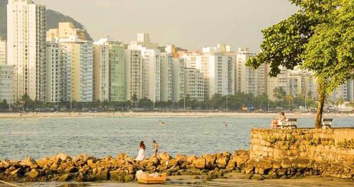 Apartamento Na Praia Das Astúrias في غوارويا: مجموعة من الناس على الشاطئ بالقرب من المياه