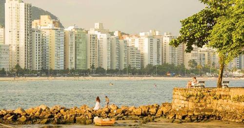 a group of people on the beach near the water at Apartamento Na Praia Das Astúrias in Guarujá