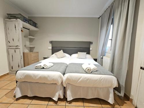 1 dormitorio con 1 cama grande y toallas. en Hostal La Campana, en Toledo