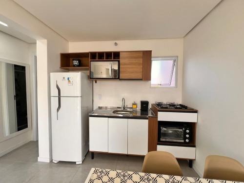 a small kitchen with a refrigerator and a sink at Los Hermanos Residencial in Florianópolis