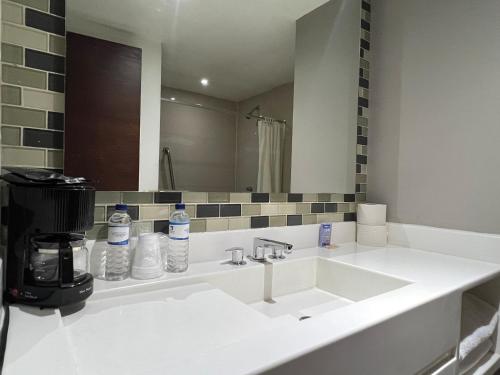 Hotel El Sembrador في Guasave: حمام مع حوض أبيض ومرآة