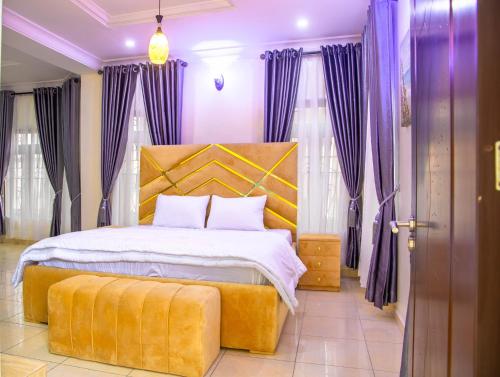 a bedroom with a large bed with purple curtains at House 4 Guest House & Apartments in Lagos