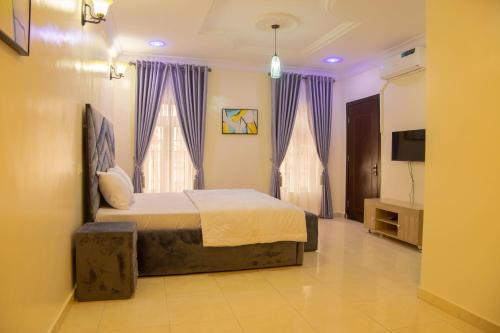 1 dormitorio con 1 cama con cortinas moradas y TV en House 4 Guest House & Apartments en Lagos