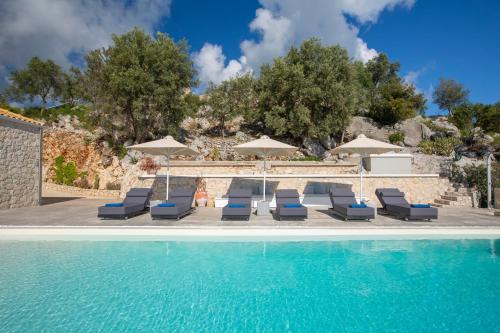 a swimming pool with lounge chairs and umbrellas at Rachi Sea View White Villa in Episkopos