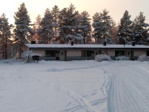 a house in the snow with trees in the background at Karhunkierrospysäkki in Salla