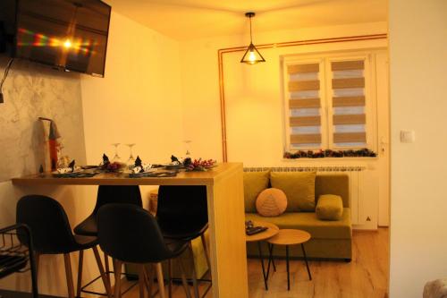 una sala de estar con un sofá, una mesa y sillas en Kovac Inalux Apartmani, en Gornje Pale