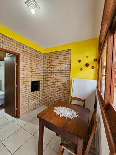um quarto com uma mesa de madeira e uma parede de tijolos em Pousada Capricórnio em Guarda do Embaú