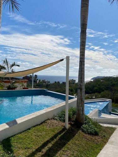 a swimming pool with a palm tree next to a house at Playa & Piscina en Punta Gaviota in Tangolunda