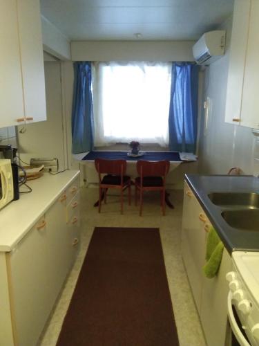 a kitchen with a sink and a table with a window at Karhunkierrospysäkki in Salla