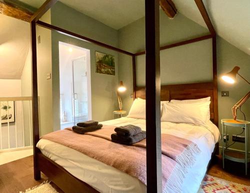 a bedroom with a canopy bed with two towels on it at Tetbury Cottage 