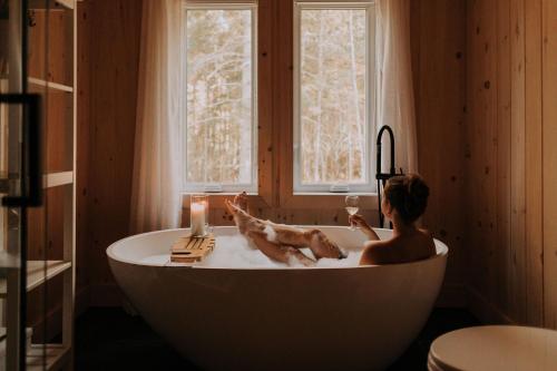 a woman in a bath tub with a glass of wine at Chalet le Chardonnay - Spa , Foyers , Accès plage Lac-Jaune in Chertsey