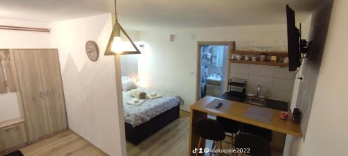 Una pequeña habitación con una cama y un escritorio y una cocina. en Kovac Inalux Apartmani, en Gornje Pale