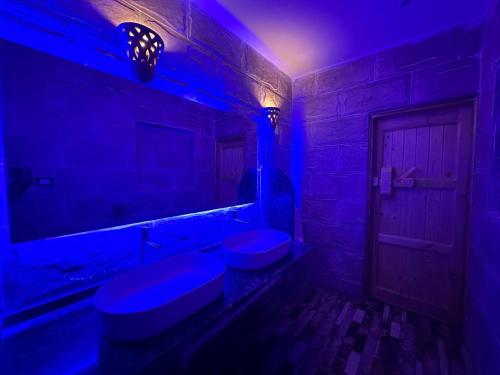 a bathroom with two toilets and a blue light at ACHERTOD NUBIAN HOTEL in Naj‘ al Maḩaţţah