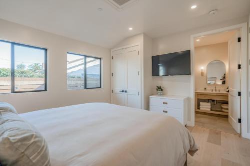 a white bedroom with a large bed and a television at Villa Castillo 4 in Santa Barbara