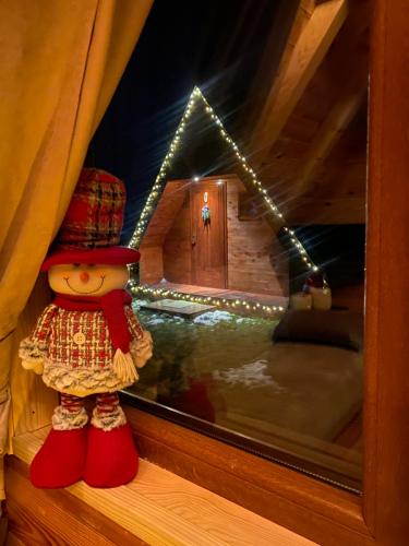 a teddy bear sitting on a window sill with a house at Blue Village 8 in Kolašin