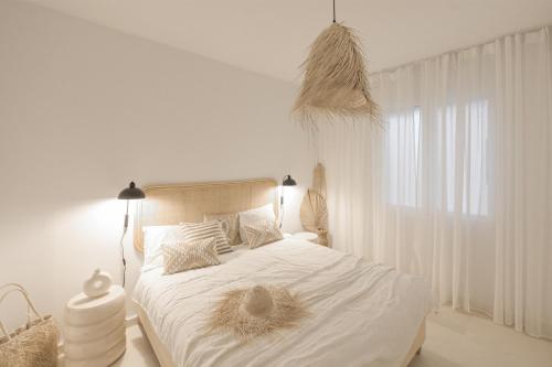 a white bedroom with a bed with white sheets and a window at Coco Calpe in Calpe