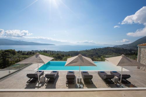 a view of a swimming pool with chairs and umbrellas at Rachi Sea View White Villa in Episkopos