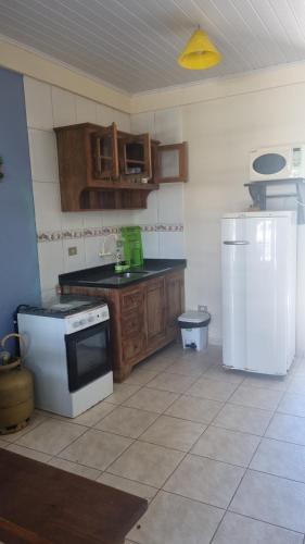 eine Küche mit einem weißen Herd und einem Kühlschrank in der Unterkunft Chalé Carvalho - Azul in Itapoa