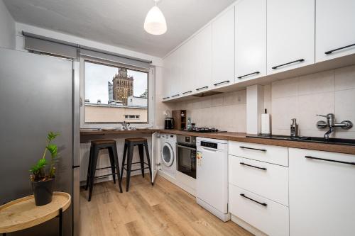 a kitchen with white cabinets and a sink and a dishwasher at Apart D&K Apartanent w centrum Warszawy in Warsaw