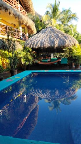 a swimming pool with a straw umbrella and a resort at Villas La Bella Margarita in Brisas de Zicatela