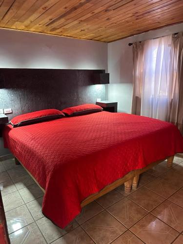 a bedroom with a red bed with a red blanket at The valley in Creel