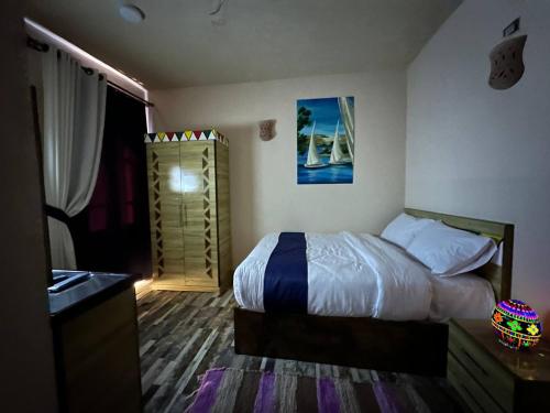 a bedroom with a bed and a dresser in it at ACHERTOD Nubian House in Naj‘ al Maḩaţţah